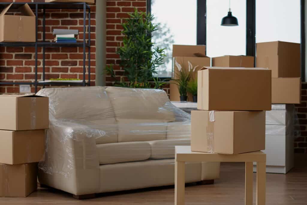 A living room with packed furniture and household items in the concept of moving houses.