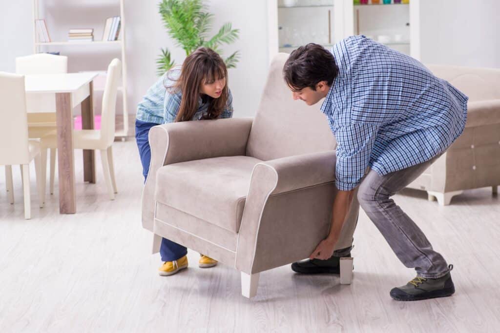 A couple lifting a bulky armchair