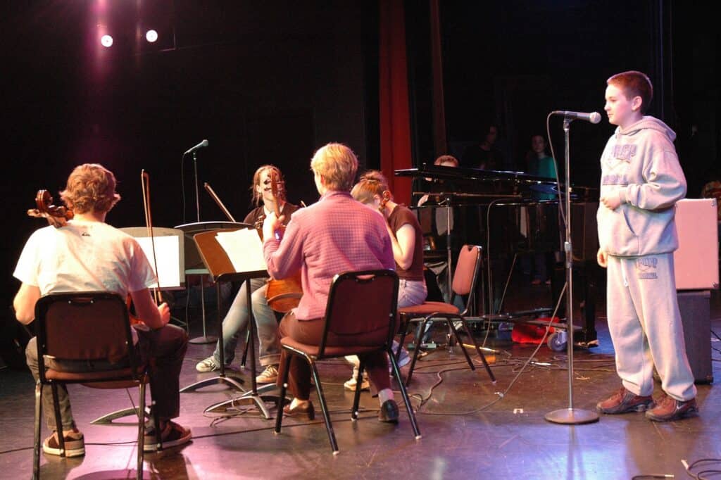 Students and a teacher holding string instruments during a music class